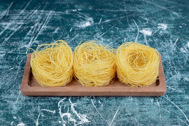 Kostenloses Foto stapel roher spaghetti-nester auf holzbrett.