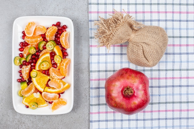 Stapel von frischen Bio-Fruchtscheiben mit ganzem Granatapfel auf grauem Tisch. Draufsicht.