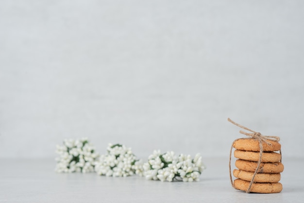 Stapel von Keksen mit weißer Blume auf weißer Oberfläche.