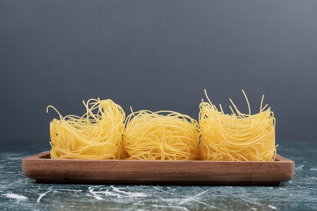 Stapel von rohen spaghetti-nestern auf holzbrett. hochwertiges foto