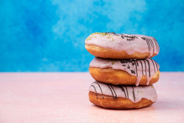 Stapel von rosa Erdbeer-Donuts auf rosa Tisch.