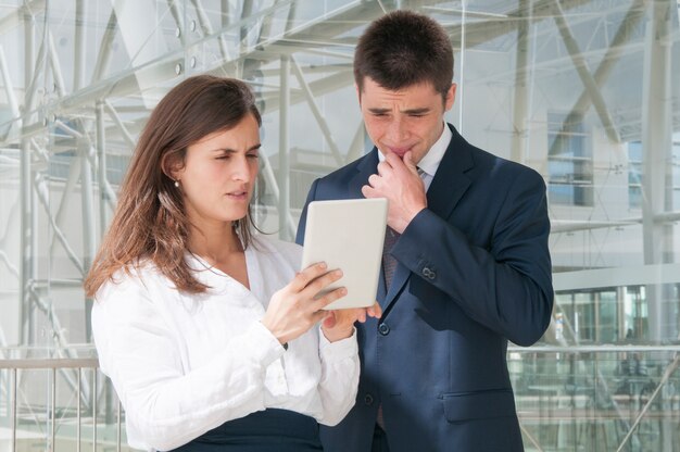 Starke Frau, die Manndaten bezüglich der Tablette, stark denkend zeigt