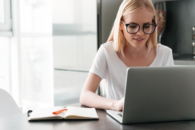 Starke junge Dame, die zu Hause mit Laptop arbeitet