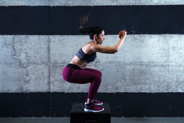 Starke muskulöse Fitness-Frau in sportlicher Kleidung beim Sprungtraining im Fitnessstudio