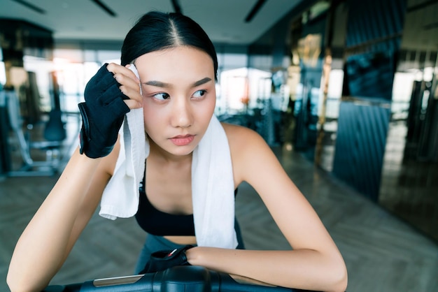 Starke und feste asiatische Frauensportkleidung entspannen sich auf Fahrradhandgriff weißen Servietteneignungshintergrund