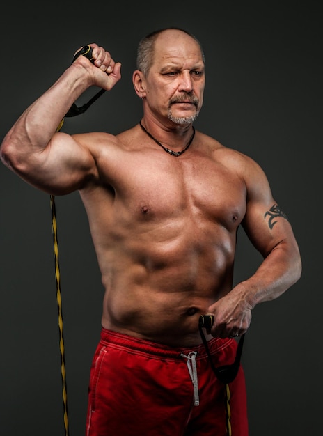 Starker muskulöser Mann mittleren Alters posiert im Studio. Isoliert auf grau.