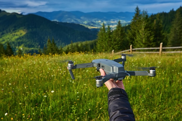 Starten Sie die Drohne aus den Händen Moderner kleiner Copter mit Kamera in der Hand des Benutzers gegen den Himmel