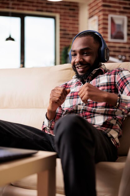 Startup-Business-Mitarbeiter, die Musik oder Podcast-Shows auf der Online-Website hören und soziale Medien und Kopfhörer verwenden, um aus der Ferne zu arbeiten. Arbeiten Sie zu Hause am Laptop und genießen Sie zu Hause Songs im Internet.