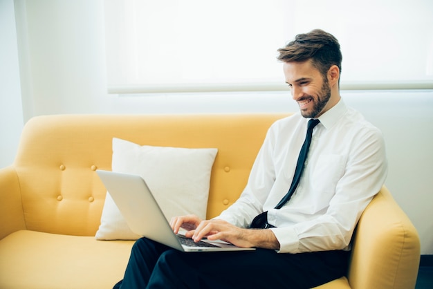 Stattlicher Geschäftsmann, lachend und mit seinem Laptop arbeitet