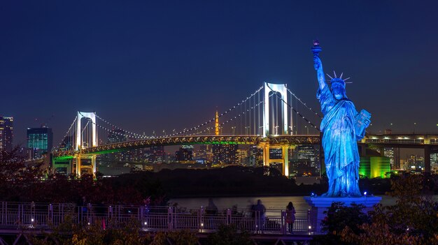 Statue und Regenbogenbrücke in der Nacht, in Tokio, Japan.