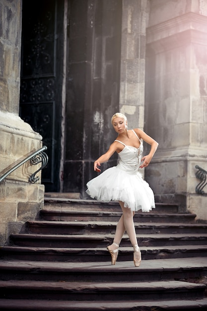 Statuenhafte Ballerina. Junge Ballerina, die ganz weiß trägt, übt in einem alten Schloss