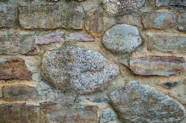 Steingraue Wand aus rohen, rauen Steinhintergrundtextur Steinen unterschiedlicher Größe Idee für Haus- oder Gebäudefassadengestaltung und öffentlichen Raum