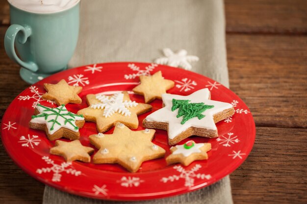 Sternförmige Cookies auf einem roten Teller und Tasse mit Sahne