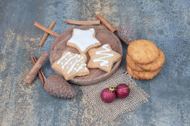 Sternförmige Lebkuchen auf Teller mit Weihnachtskugeln. Hochwertiges Foto