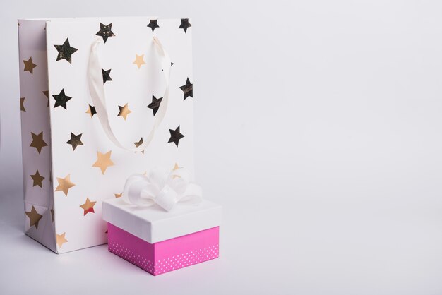 Sternform auf Einkaufstasche mit der geschlossenen Geschenkbox lokalisiert auf weißem Hintergrund