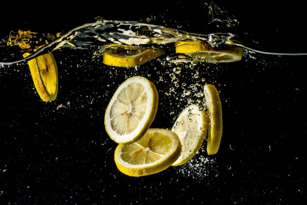 Stillleben Fotografie aufgenommen von Zitronenscheiben, die unter Wasser fallen und einen großen Spritzer machen