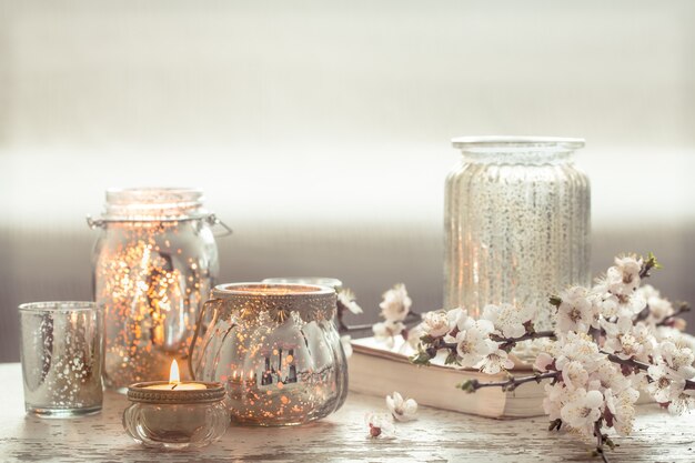 Stillleben. Home gemütliche schöne Einrichtung im Wohnzimmer, eine Vase mit Frühlingsblumen und Kerzen auf einem hölzernen Hintergrund, das Konzept der Innendetails