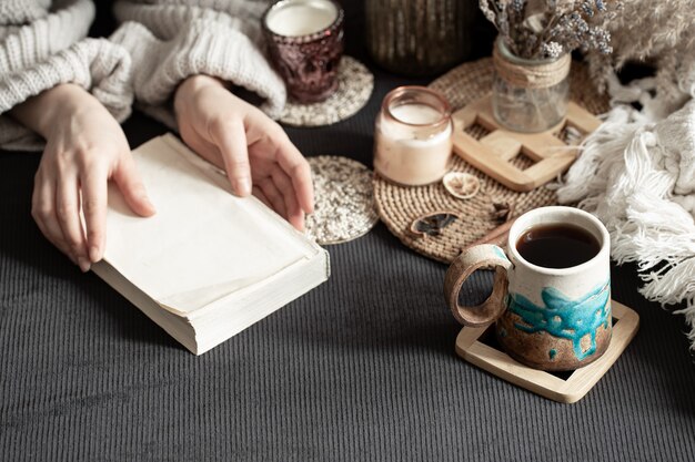 Stillleben mit einer schönen Tasse und weiblichen Händen. Eine intime, heimelige Atmosphäre. dekorative Gegenstände.