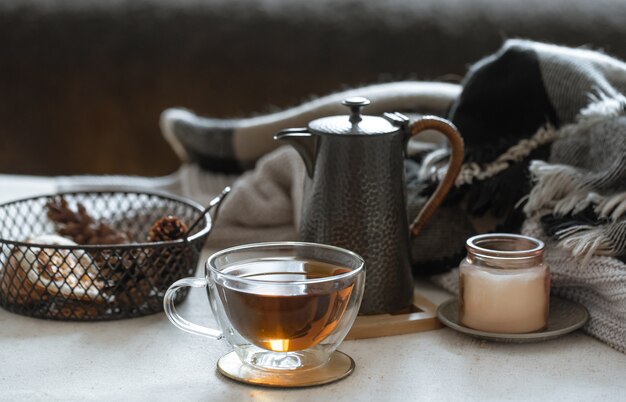 Stillleben mit einer Tasse Tee, einer Teekanne, einem Buch und Dekordetails auf einem unscharfen Hintergrund.