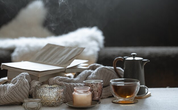 Stillleben mit einer Tasse Tee, einer Teekanne, einem Buch und wunderschönen Vintage-Kerzenleuchtern mit Kerzen. Wohnkultur-Konzept.