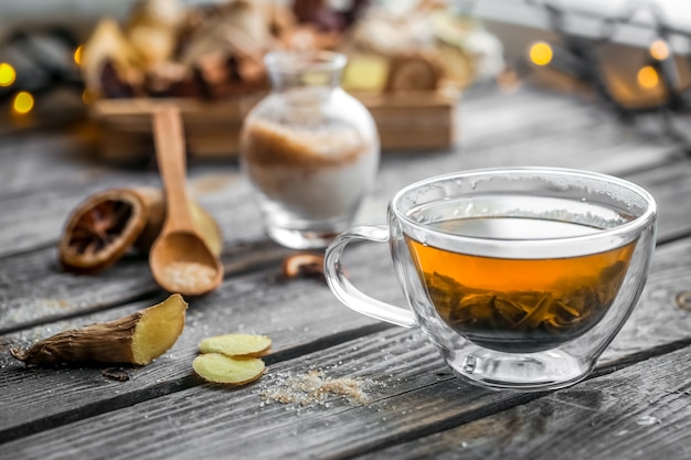 Stillleben mit transparenter Tasse Tee auf hölzernem Hintergrund