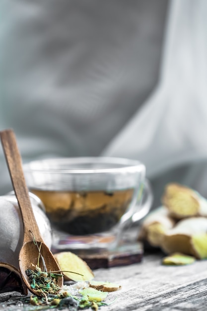 Stillleben mit transparenter Tasse Tee auf hölzernem Hintergrund