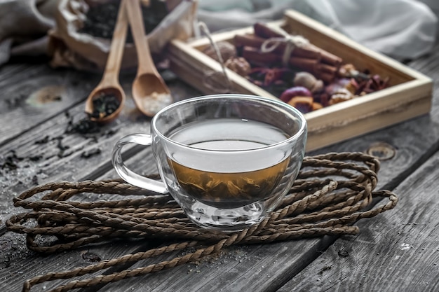 Stillleben mit transparenter und duftender Tasse Tee mit Ingwer auf hölzernem Hintergrund