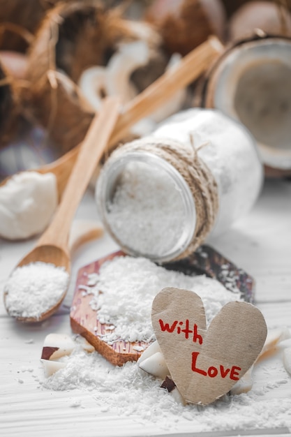 Stillleben Valentinstag mit Kokosnuss und Herz, Holzlöffel mit Kokosnuss auf Holzhintergrund