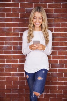 Stilvolle blondine, die smartphone lächeln und verwenden