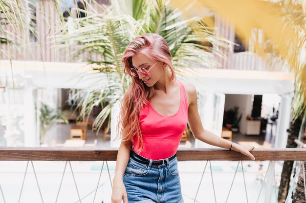 stilvolle emotionale Frau, die mit ihren langen rosa Haaren am Sommertag spielt.