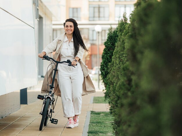 Stilvolle erwachsene Frau, die mit umweltfreundlichem Fahrrad aufwirft