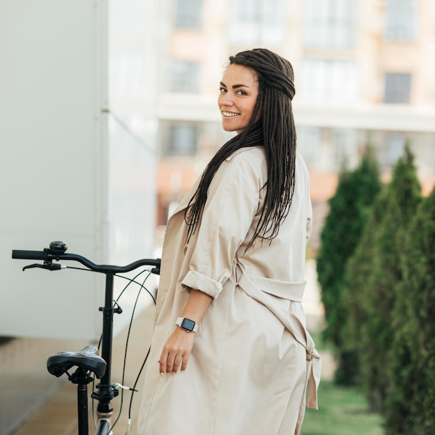 Stilvolle erwachsene Frau, die mit umweltfreundlichem Fahrrad aufwirft