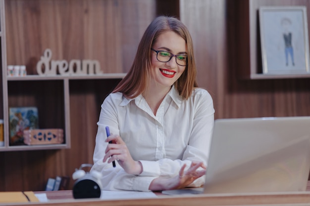 Stilvolle Frau arbeitet an einem Laptopschreibtisch in einem modernen Büro