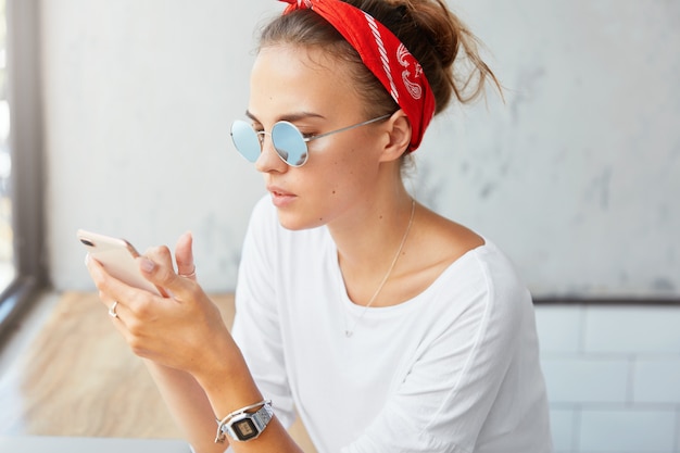 Stilvolle Frau, die Bandana trägt, sitzt im Café