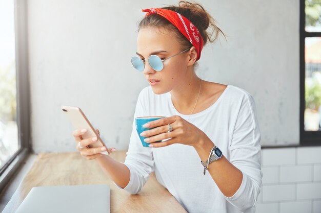 Stilvolle Frau, die Bandana trägt, sitzt im Café