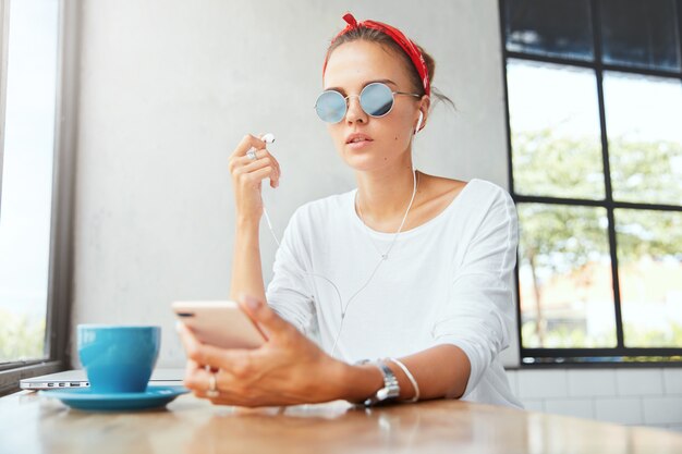 Stilvolle Frau, die Bandana trägt, sitzt im Café