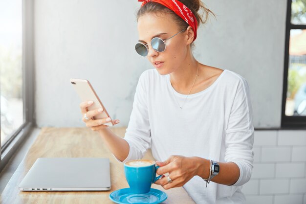 Stilvolle Frau, die Bandana trägt, sitzt im Café