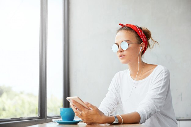 Stilvolle Frau, die Bandana trägt, sitzt im Café