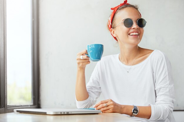 Stilvolle Frau, die Bandana trägt, sitzt im Café