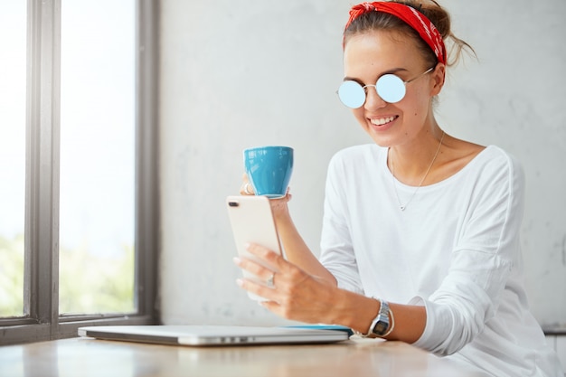 Stilvolle Frau, die Bandana trägt, sitzt im Café