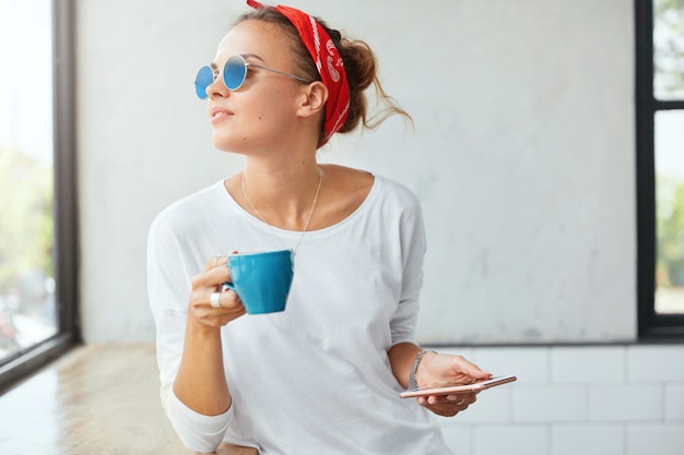 Stilvolle Frau, die Bandana trägt, sitzt im Café