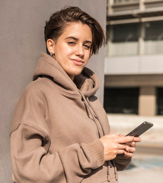 Stilvolle Frau, die Sportbekleidung trägt und ihr Telefon hält