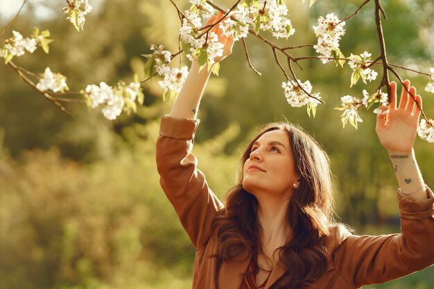 Stilvolle Frau, die Zeit in einem Frühlingspark verbringt