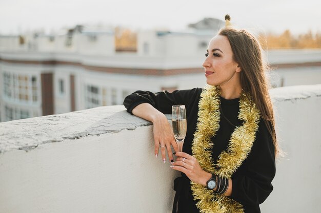 Stilvolle Frau im schwarzen Kleid mit einem Glas Champagner