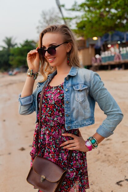Stilvolle Frau im Sommerkleidurlaub, der auf Strand mit Sonnenbrille geht
