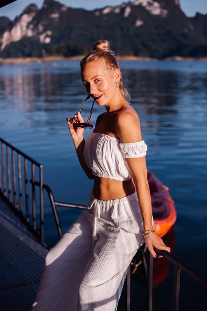 Stilvolle Frau in weißem Crop-Top und Hose mit hoher Taille