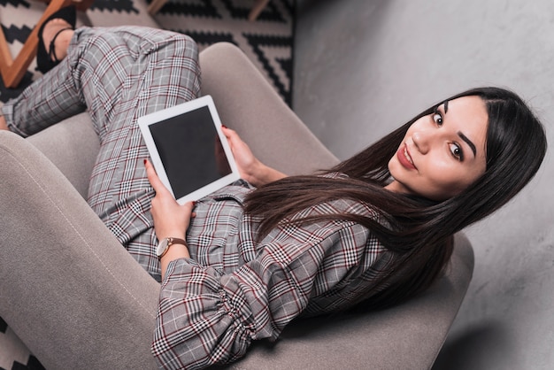 Stilvolle Frau mit der Tablette, die Kamera betrachtet