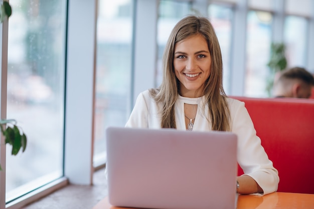 Stilvolle Frau mit Smiley-Gesicht mit einem Laptop vor