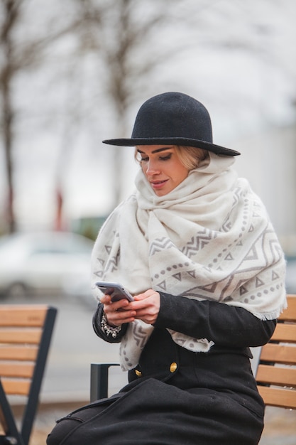 Stilvolle Frau sitzt auf einer Bank