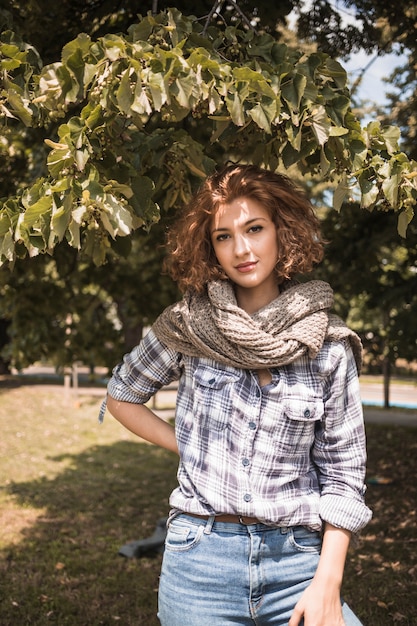 Stilvolle Frau unter Baum im Park